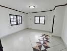 spacious white living room with decorative floor tiles and two windows