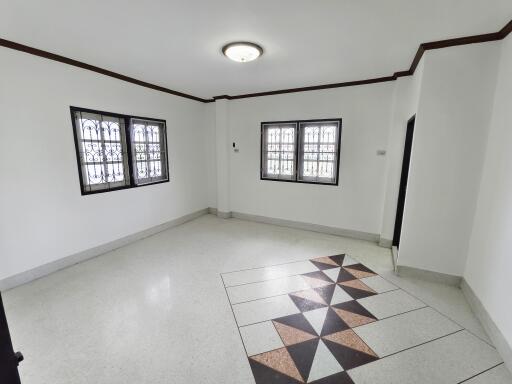 spacious white living room with decorative floor tiles and two windows