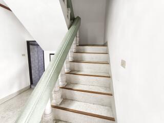 Interior staircase with white steps and green handrail