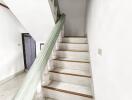 Interior staircase with white steps and green handrail