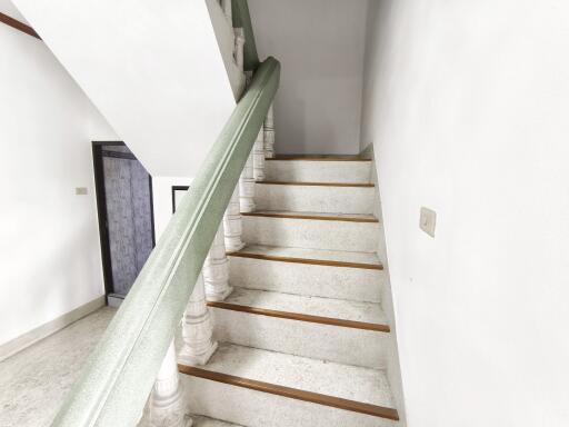 Interior staircase with white steps and green handrail