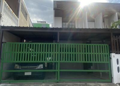 Front view of the house with green gate and covered carport