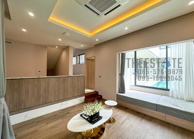 Modern living room with wooden flooring, recessed lighting, and a view of the pool