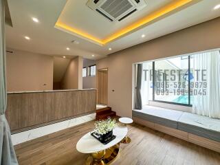 Modern living room with wooden flooring, recessed lighting, and a view of the pool