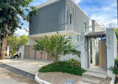 Modern two-story house exterior with driveway and greenery