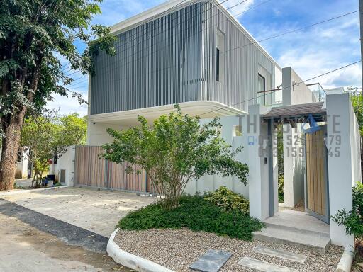 Modern two-story house exterior with driveway and greenery