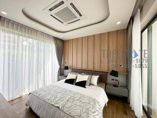 Modern bedroom with large windows and wooden flooring