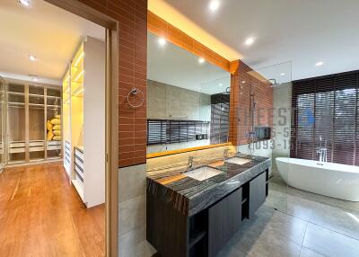 Modern bathroom with dual sinks, bathtub, and walk-in closet