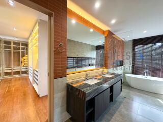 Modern bathroom with dual sinks, bathtub, and walk-in closet