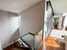 Modern staircase area with wooden flooring and glass railings