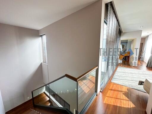 Modern staircase area with wooden flooring and glass railings