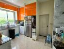 Modern kitchen with bright orange cabinets and large window