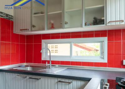 Modern kitchen with red tile backsplash and window.