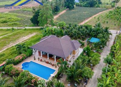 Aerial view of property with swimming pool surrounded by lush greenery