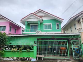 Front view of a two-story residential building with a green façade