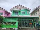 Front view of a two-story residential building with a green façade