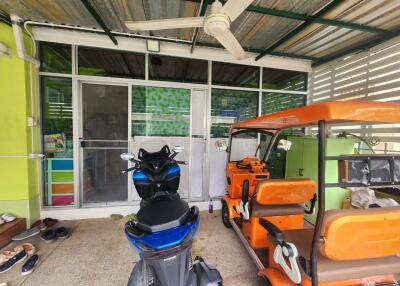 Photo of a garage with a scooter and an auto rickshaw