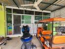 Photo of a garage with a scooter and an auto rickshaw