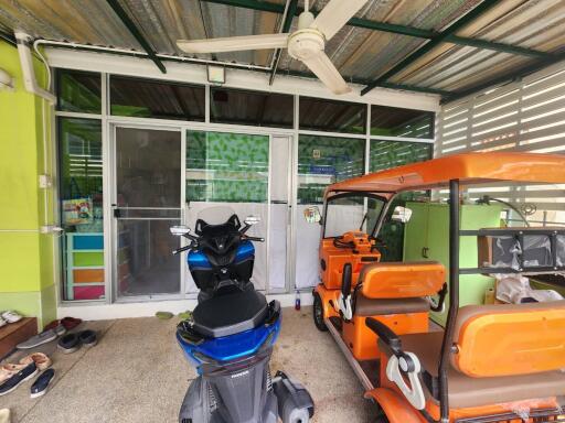 Photo of a garage with a scooter and an auto rickshaw