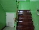 A wooden staircase with green walls