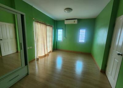 Spacious green bedroom with wooden flooring