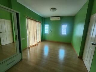 Spacious green bedroom with wooden flooring