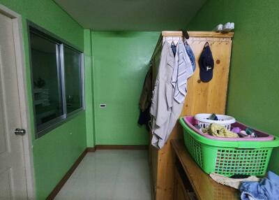 Small narrow bedroom with green walls, wooden furniture, and hanging clothes