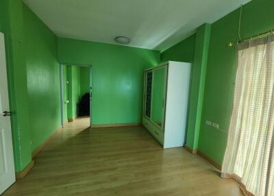 Green-painted bedroom with wooden flooring, wardrobe, and large window