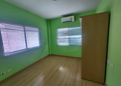 A brightly lit and freshly painted bedroom with light wooden flooring and air conditioning.