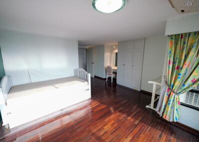 Spacious bedroom with wooden floor, single bed, desk, and ample storage