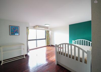 Spacious bedroom with hardwood floor and large window