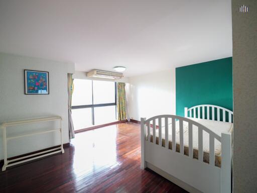 Spacious bedroom with hardwood floor and large window