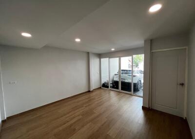 Empty living room with wooden floors and sliding glass doors leading to a garage