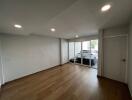 Empty living room with wooden floors and sliding glass doors leading to a garage