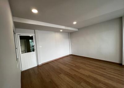 Spacious empty room with wooden flooring and recessed lighting