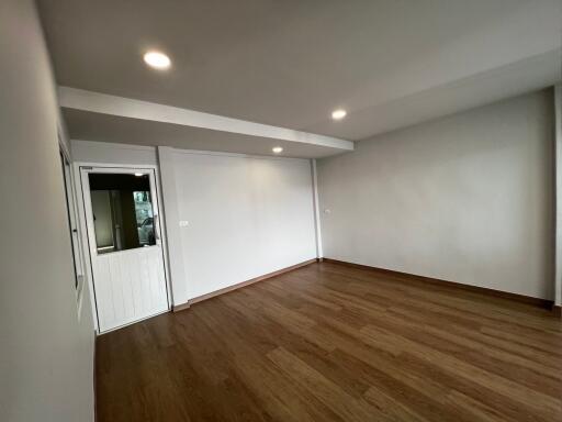 Spacious empty room with wooden flooring and recessed lighting