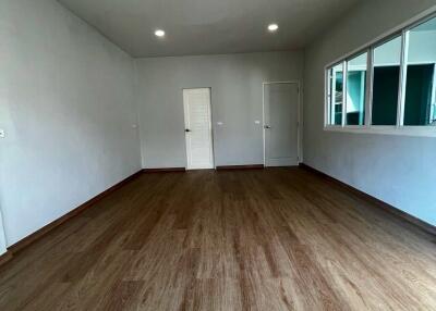 Spacious empty living room with wood flooring and white walls