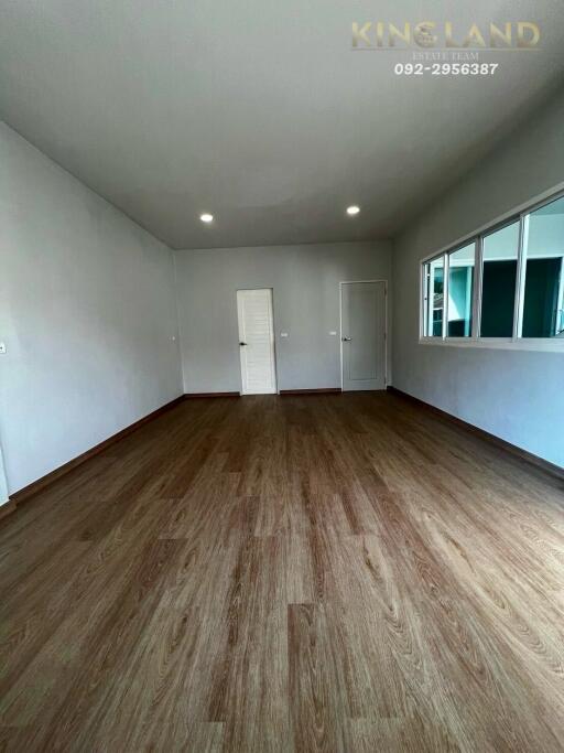 Spacious empty living room with wood flooring and white walls