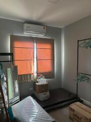 Small bedroom with air conditioner and storage items