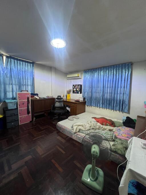 Bedroom with wooden floors, a double bed, and a freestanding fan