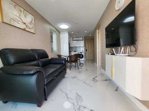 Modern living room with black sofa, large TV, and dining area