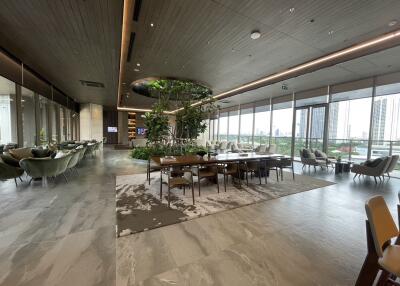 Spacious and modern communal area with large windows, ample seating, and greenery