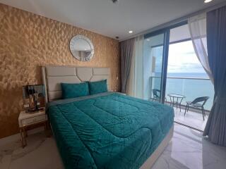 Bedroom with large bed, ocean view, and balcony access