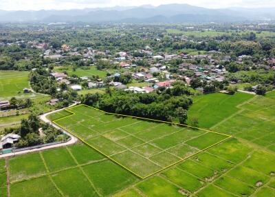 Aerial view of a plot of land with surrounding greenery and houses