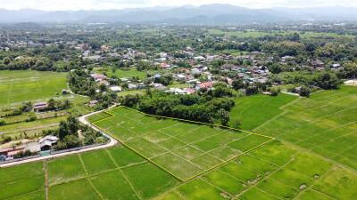 Aerial view of a plot of land with surrounding greenery and houses