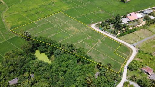 Aerial view of a land plot outlined in yellow, surrounded by greenery