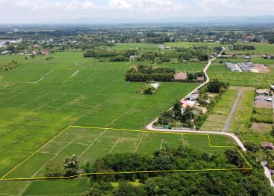 Aerial view of expansive green fields with some buildings and a road