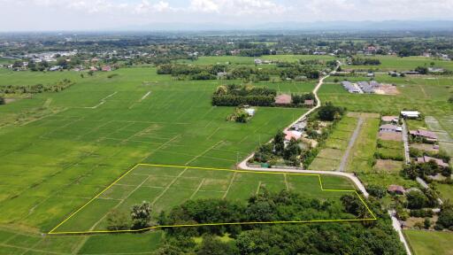 Aerial view of expansive green fields with some buildings and a road