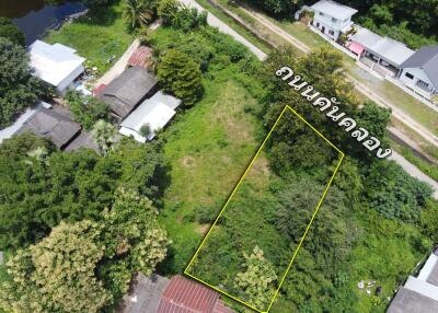 Aerial view of a vacant lot surrounded by greenery and nearby residential buildings