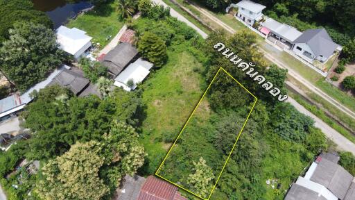 Aerial view of a vacant lot surrounded by greenery and nearby residential buildings